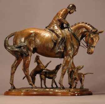 A bronze statue of a man riding a horse with dogs.