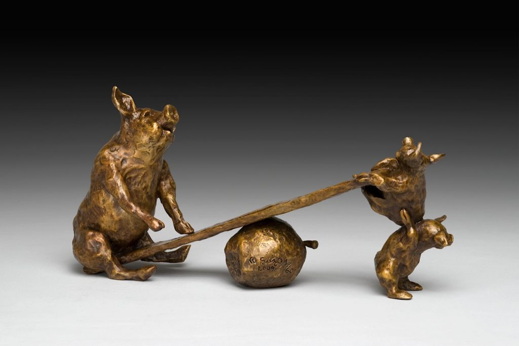 A bronze sculpture of a pig and an apple.