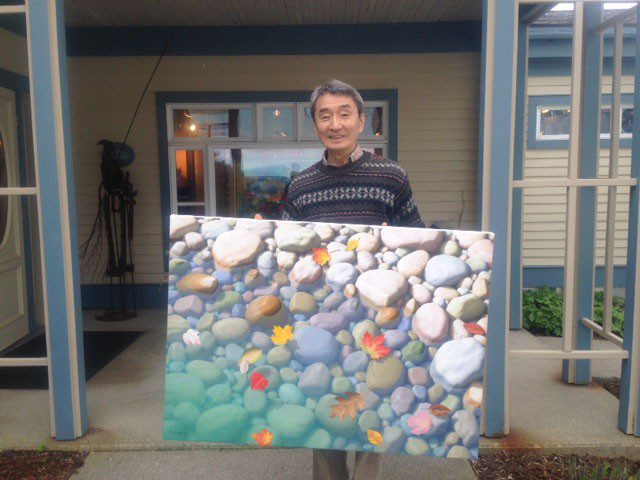 A man holding a large painting outside of a house.