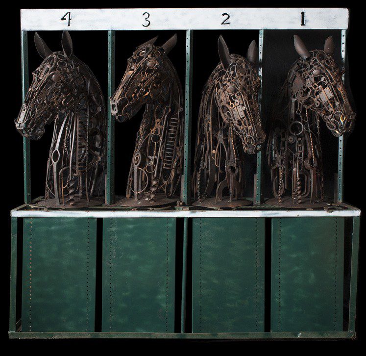 Three horse head sculptures in a display case.
