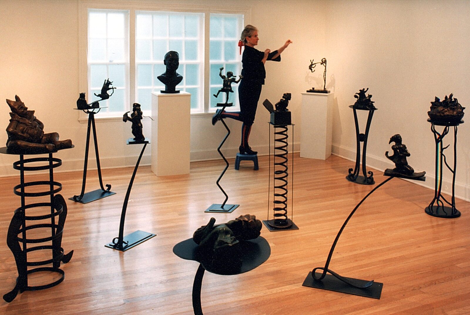 A woman standing in front of a room full of sculptures.