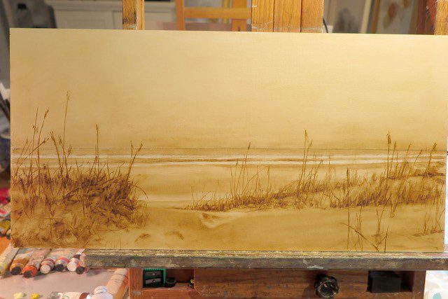 A painting of a beach scene on a easel.