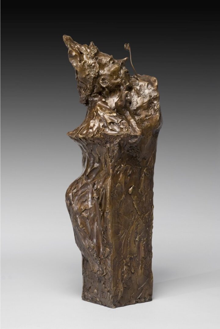 A bronze sculpture of a woman sitting on a rock.